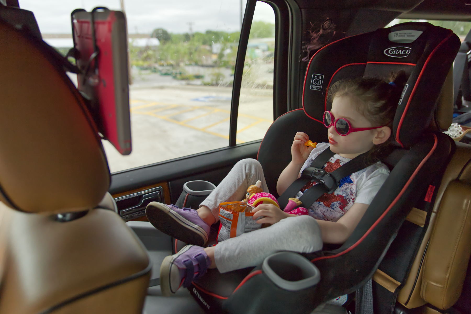 visit lawrenceburg tn alana in sunglasses Girl sitting in car seat eating and watching her ipad.
